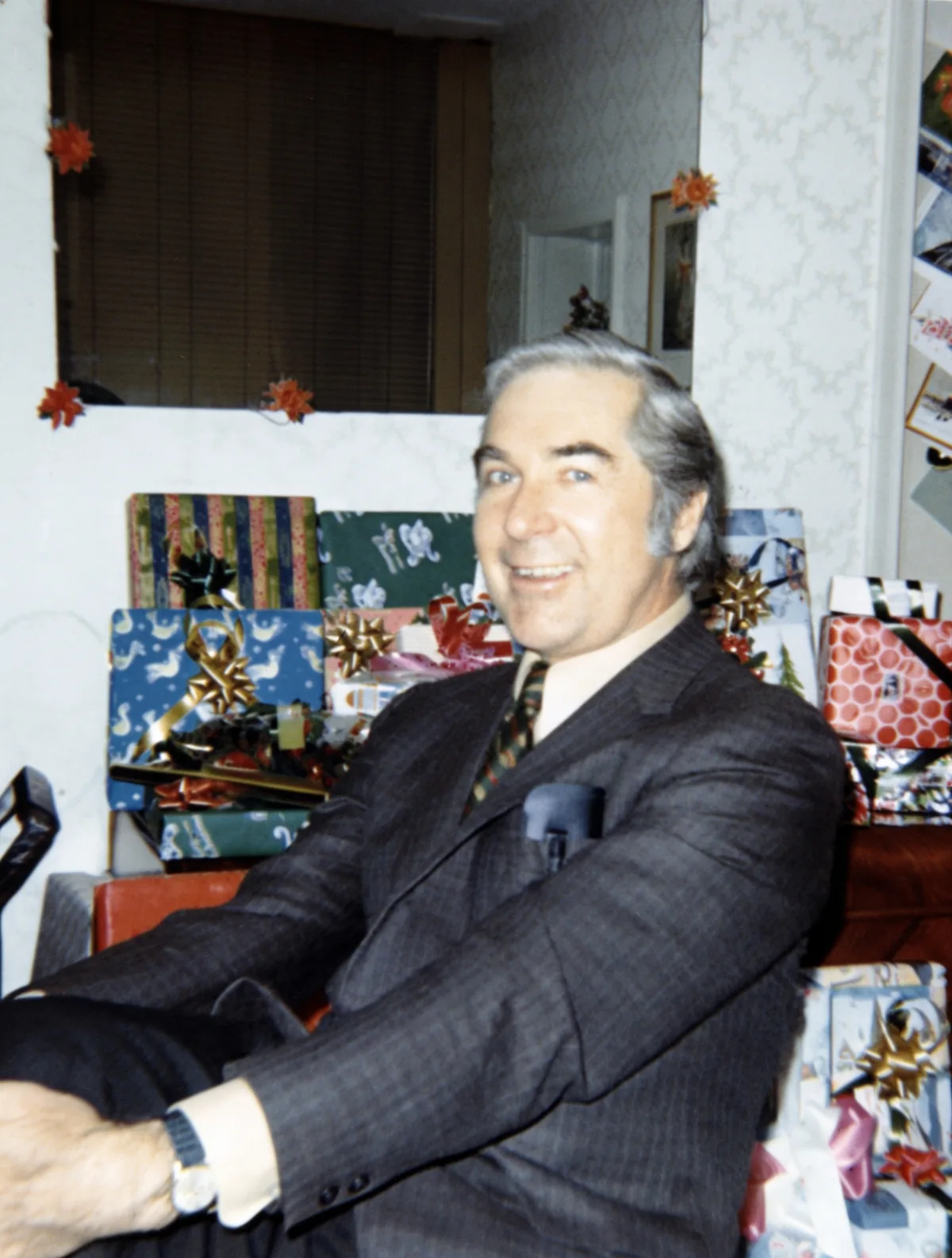 The restored 1971 photo: natural skin tones and colors, Christmas presents visible behind the man.